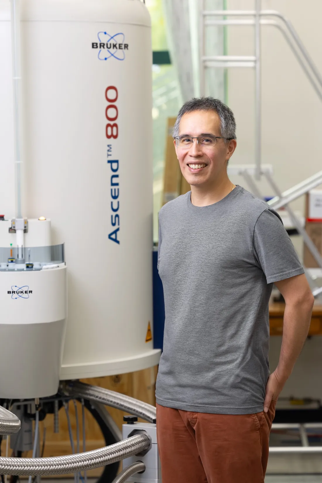 Professor Carlos Castañeda standing in front of a nuclear magnetic resonance (NMR) spectrometer.