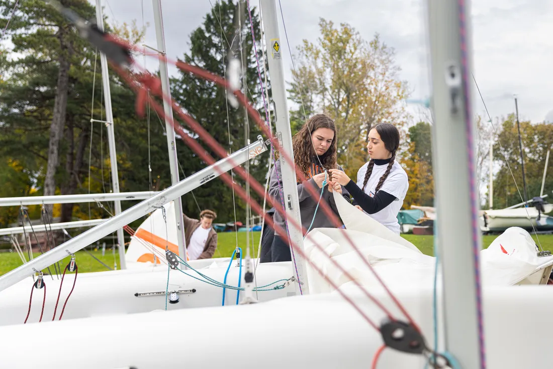 Two sailing team members maintaining their boat.