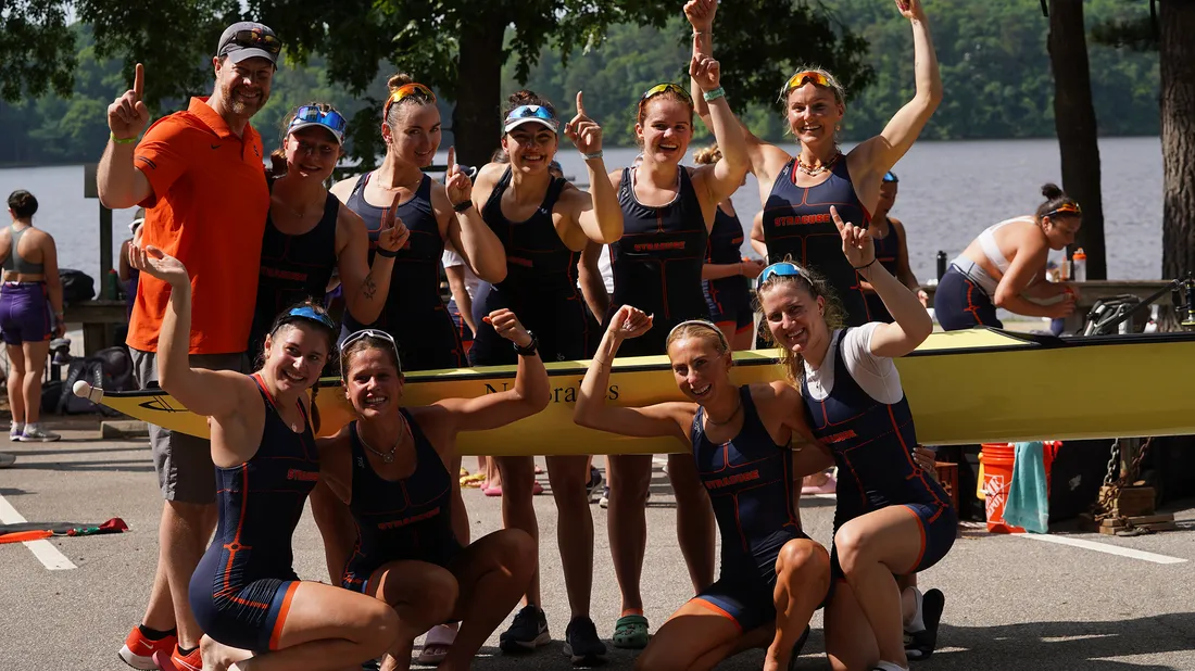 The women's rowing team poses together with their boat.