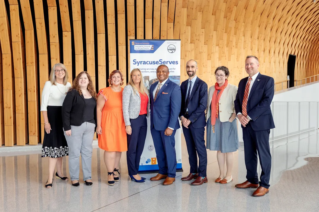 Portrait of a group of people standing in a row, smiling.