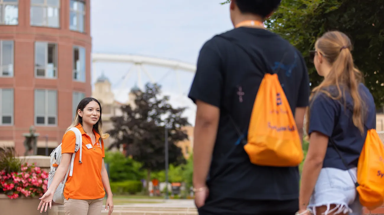 A tour guide leading students across campus at Syracuse University.