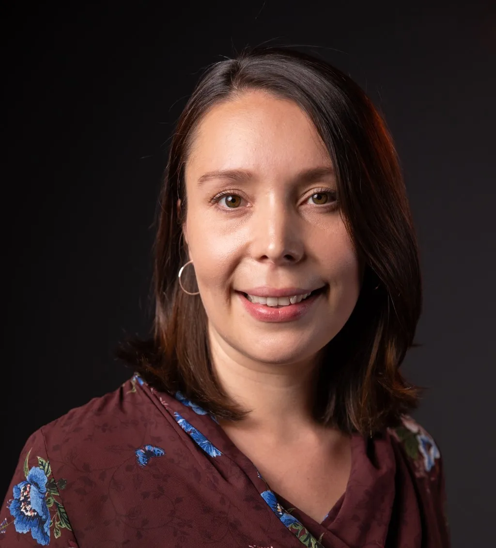 Amrita Trombetta smiling in a red floral shirt.