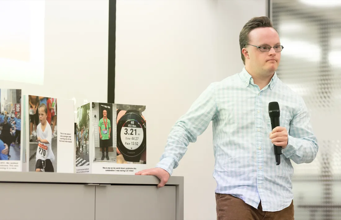 InclusiveU student Ben St. Lawrence standing at the front of a room holding a microphone.