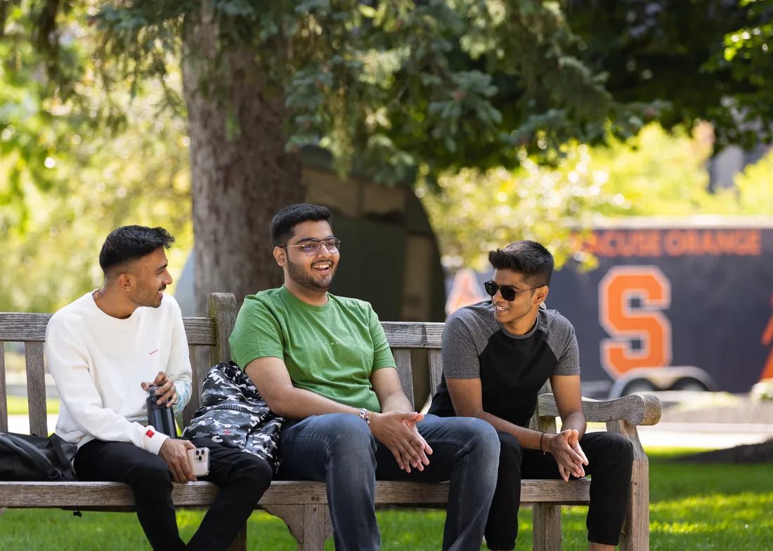 Three international students sitting on a bench.
