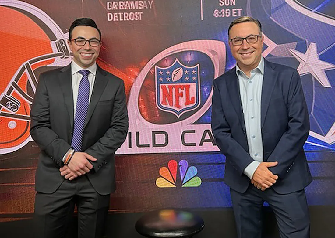 Ian and Noah Eagle standing together in front of a NFL sign.