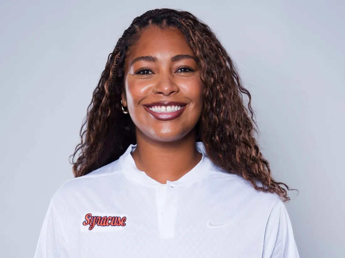 Syracuse University Women's Basketball General Manager Mykala Walker smiling in a Syracuse University sweatshirt.