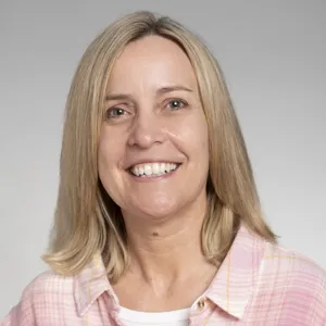 Nanette Downie smiling in a pink plaid button up.