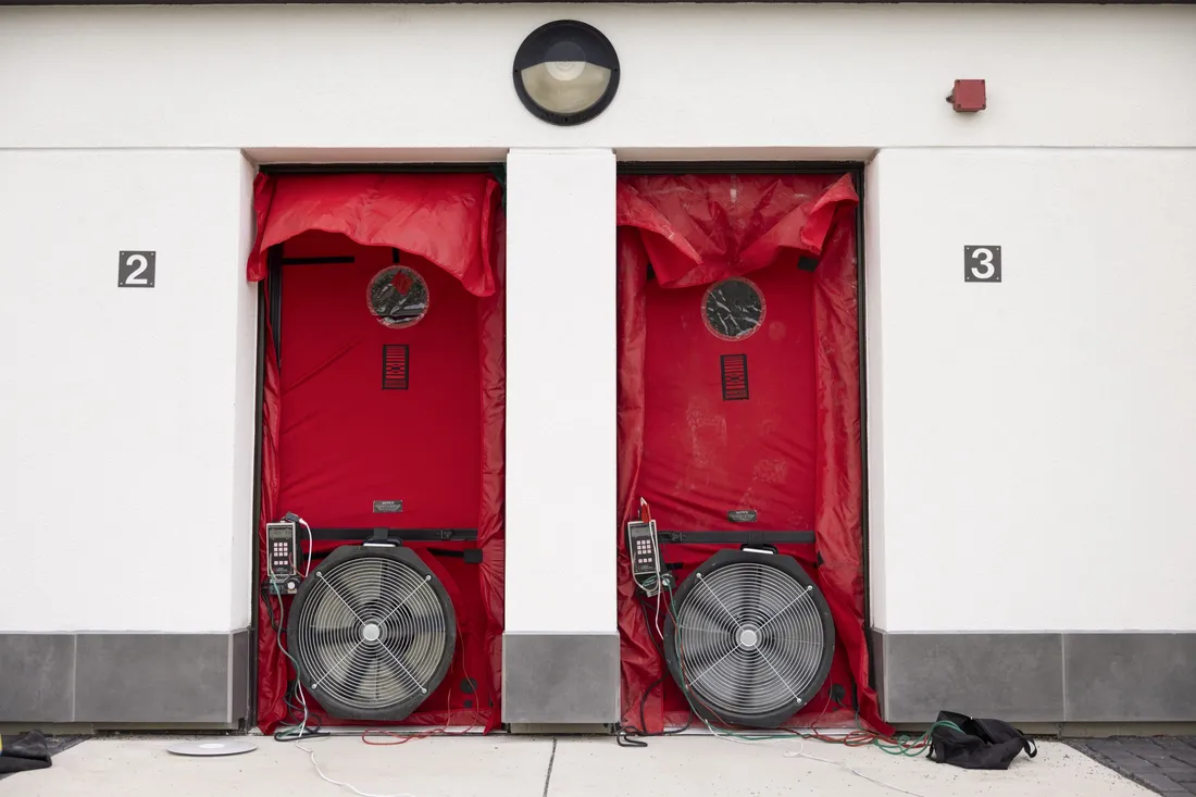 Two doors to the retrofitted apartments on South Campus, with fans and air leakage tracking technology attached.