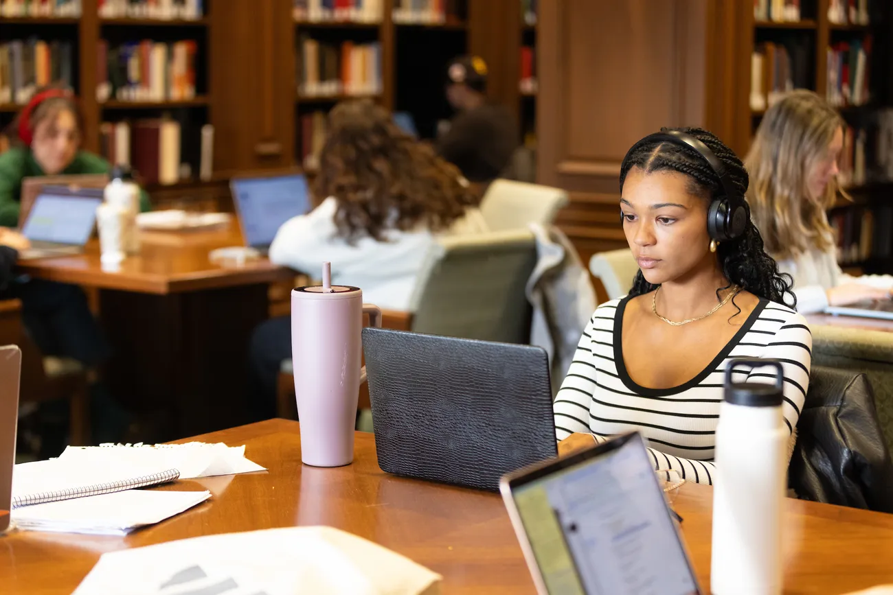 A person sitting in a library on her computer.