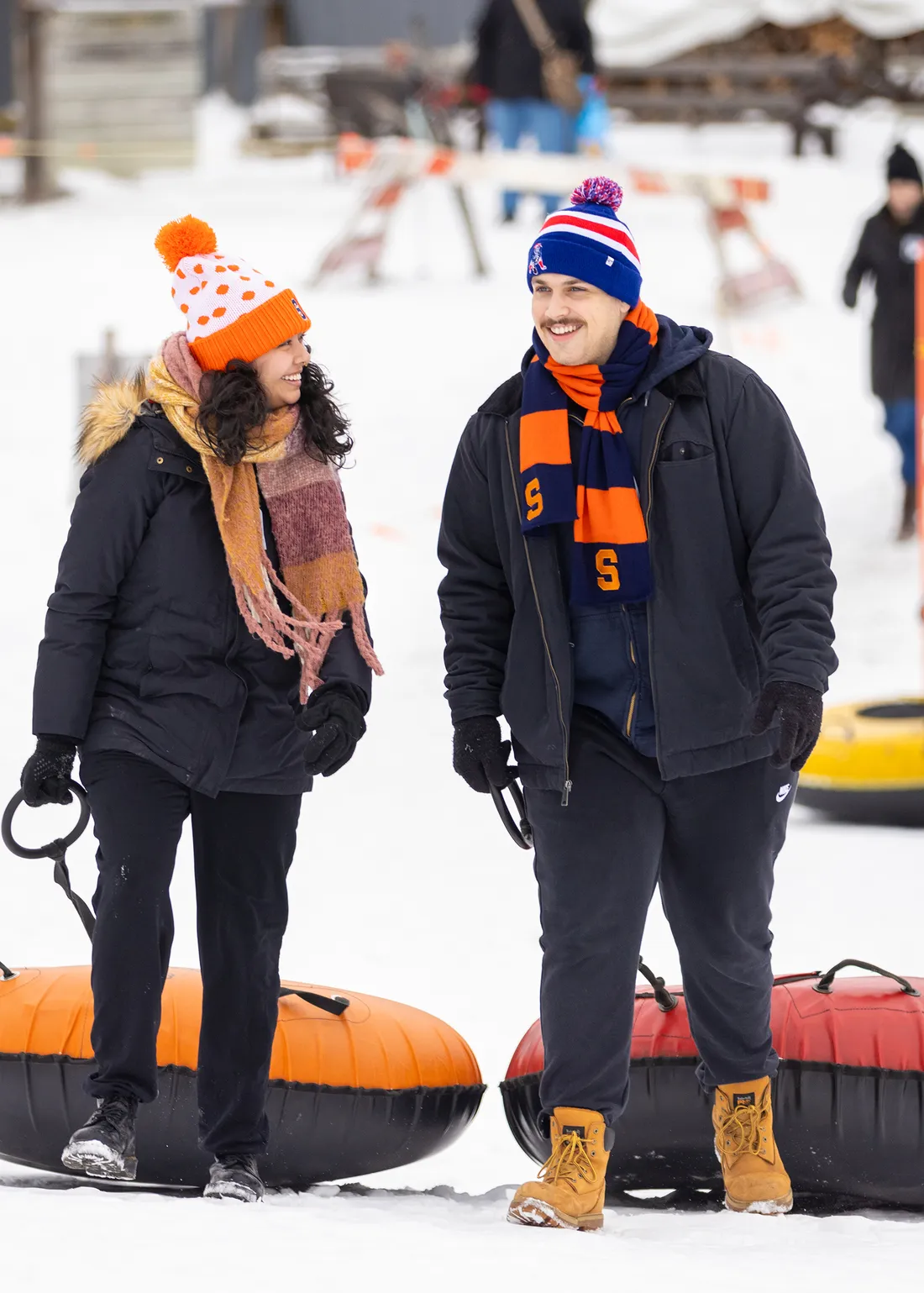 Two students holding snow tubes at a ski resort.