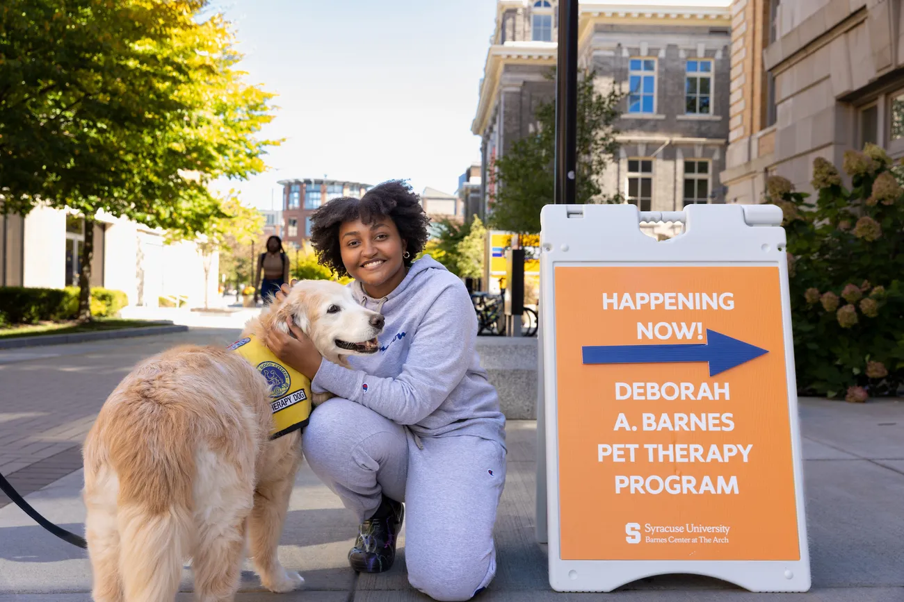 A person and a pet therapy dog outside the Barnes Center at the Arch.