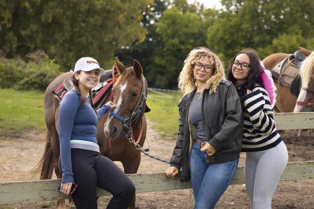 Students standing and posing with horses.