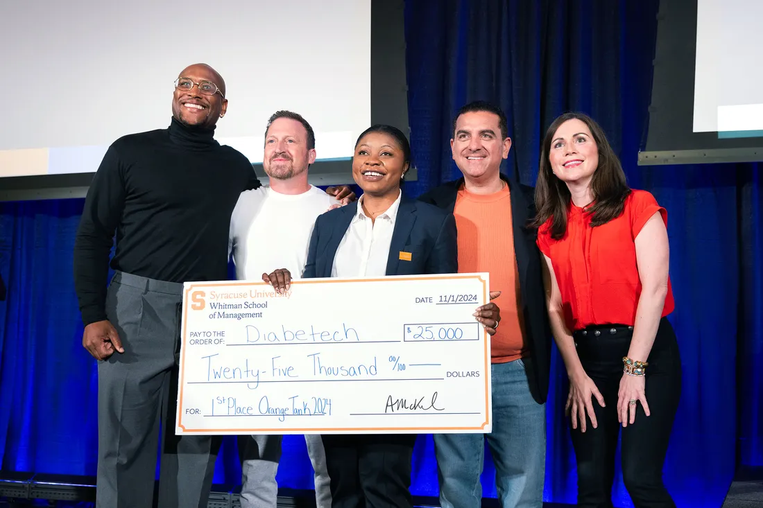 Tosin Alabi holding a big check after winning Orange Tank.