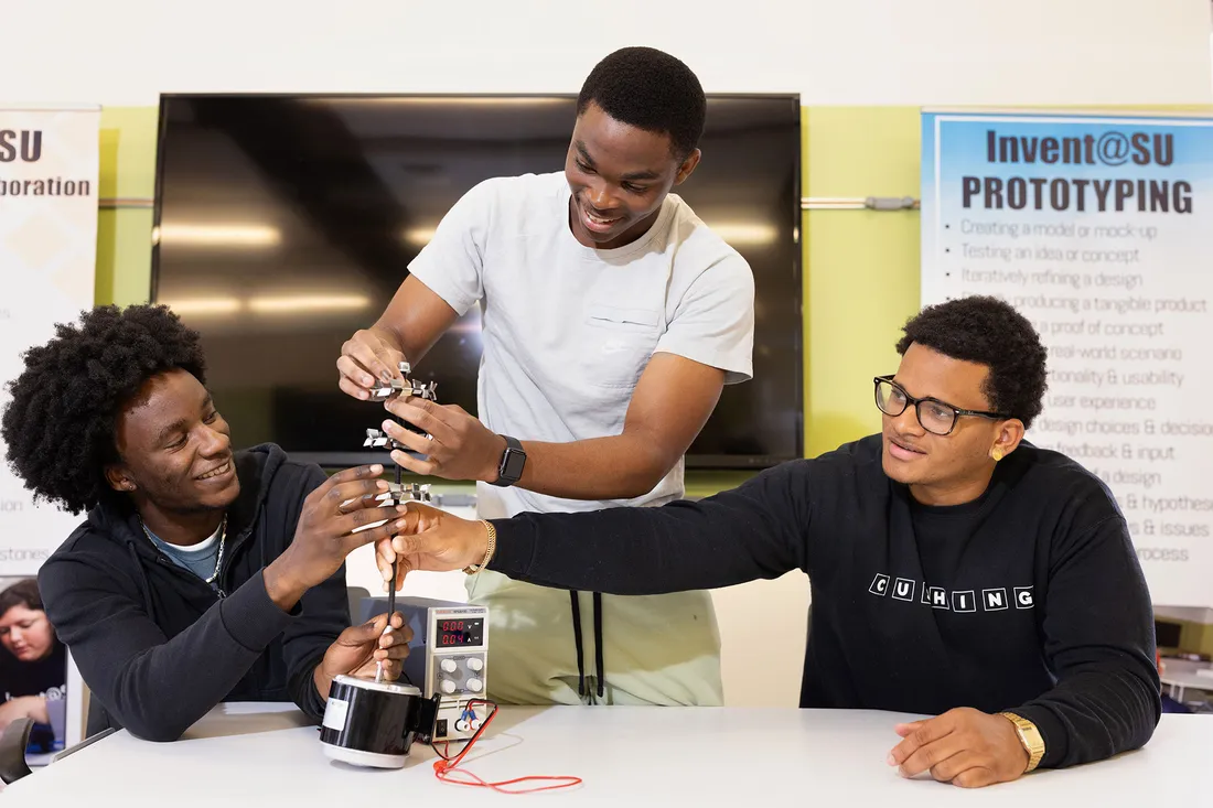 Three students work together in workshop on invention.