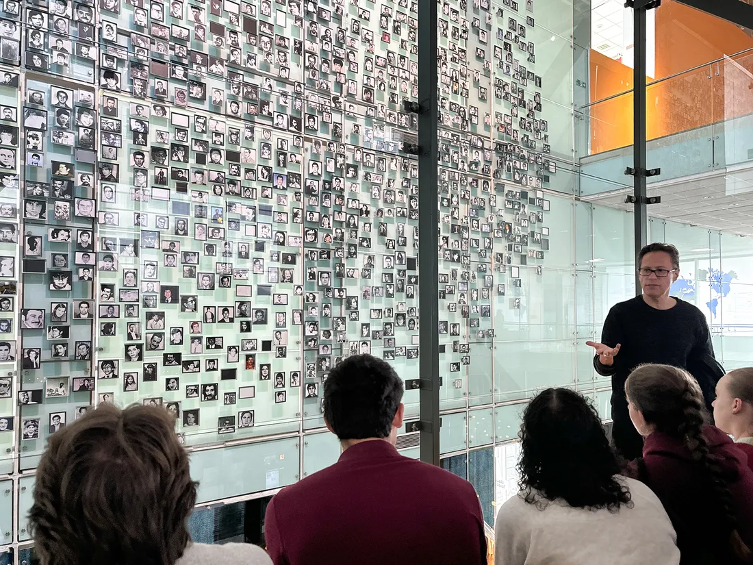 Professor teaching students in a museum with a lot of pictures.