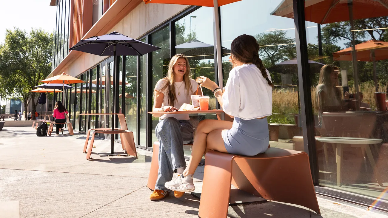 Syracuse University students sitting at an outdoor picnic table on campus.
