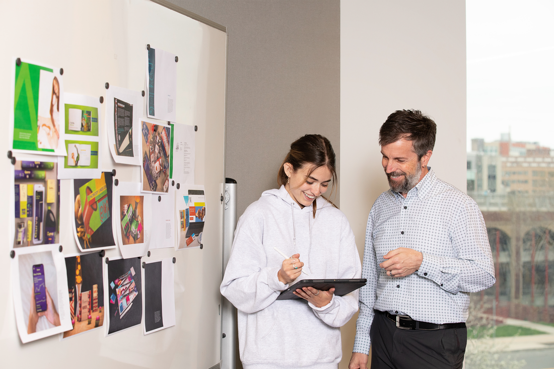 Student working with Professor Marc Stress in front of a vision board.