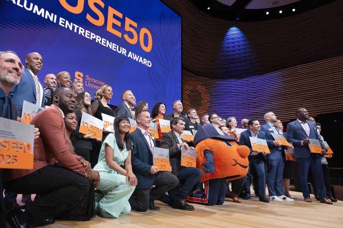 Group of people holding awards onstage at Cuse 50 with Otto the Orange.
