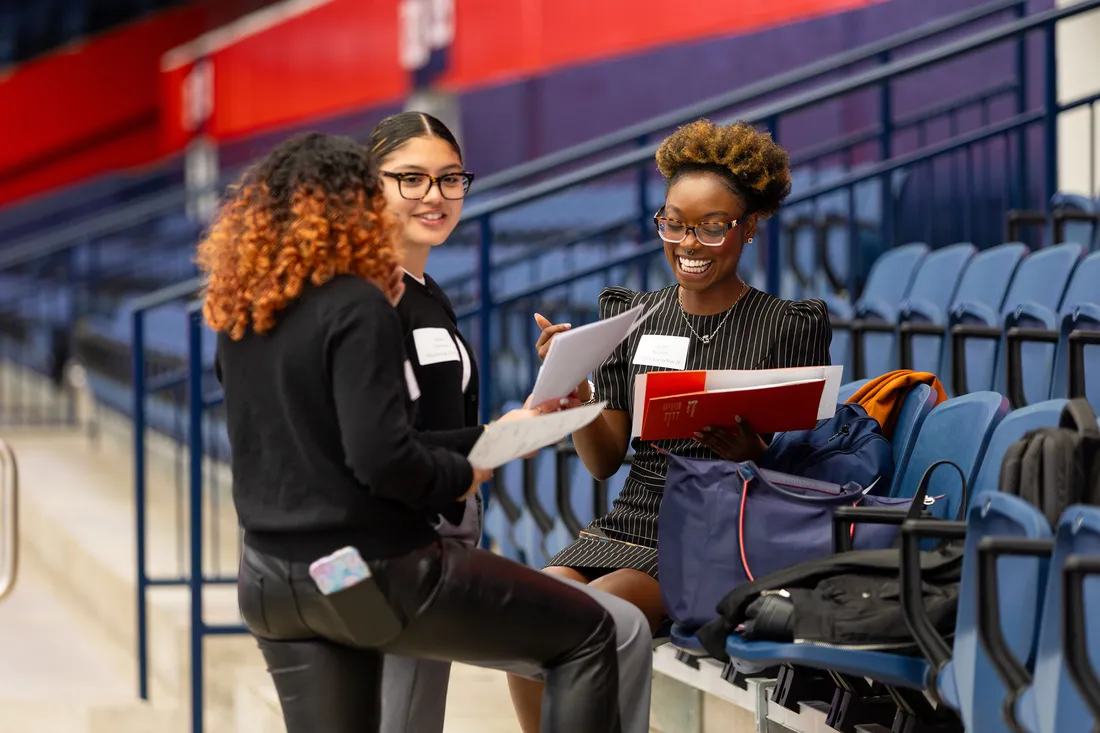 People talking on the bleachers at the JMA Wireless Dome during a career fair.