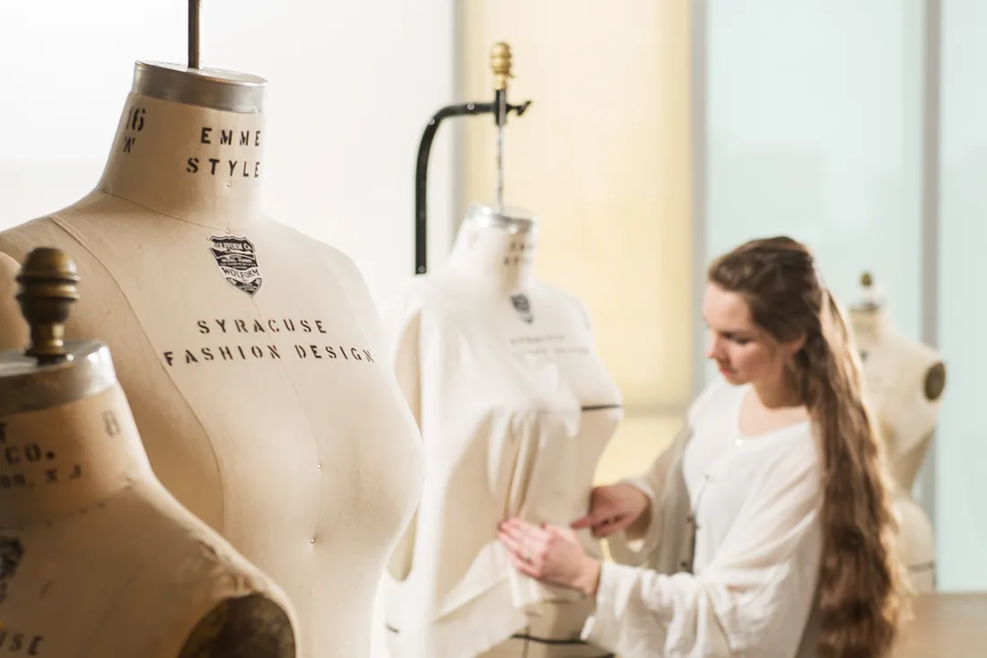 Fashion student works on a garment draping on a dressform.