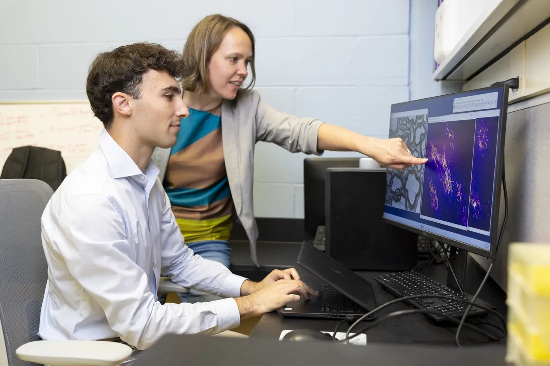 Student Beckam Polis sitting at a computer with Dr. Marie Bechler as she points at the screen.