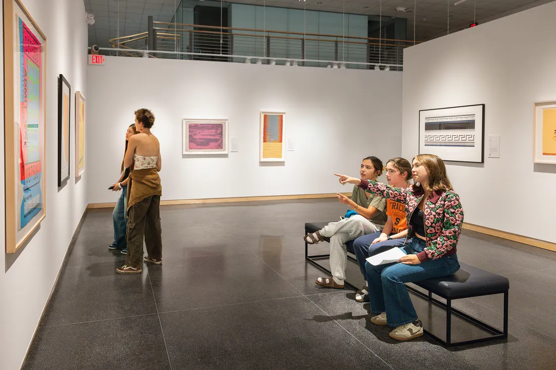 People sitting and looking at art in a museum.