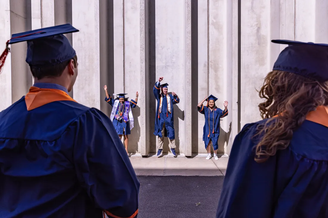 People in caps and gowns jumping.