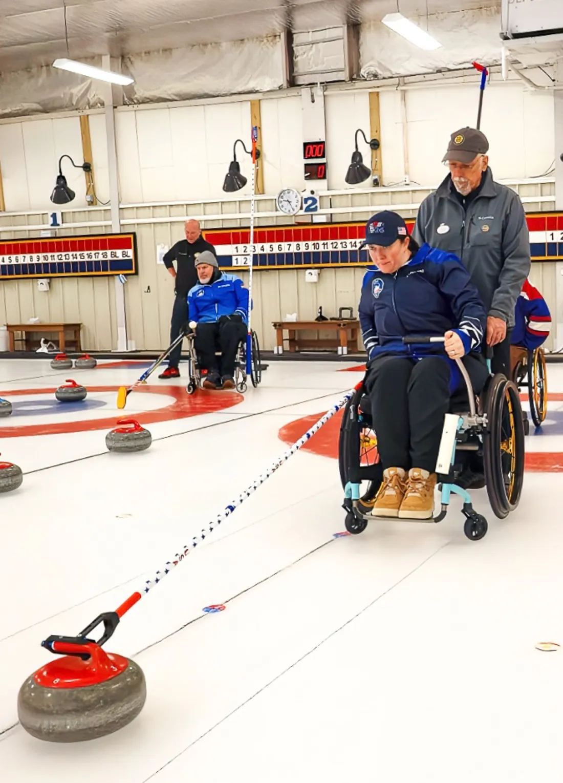 Katie Verderber on an ice rink using a mechanism to throw a curling stone.