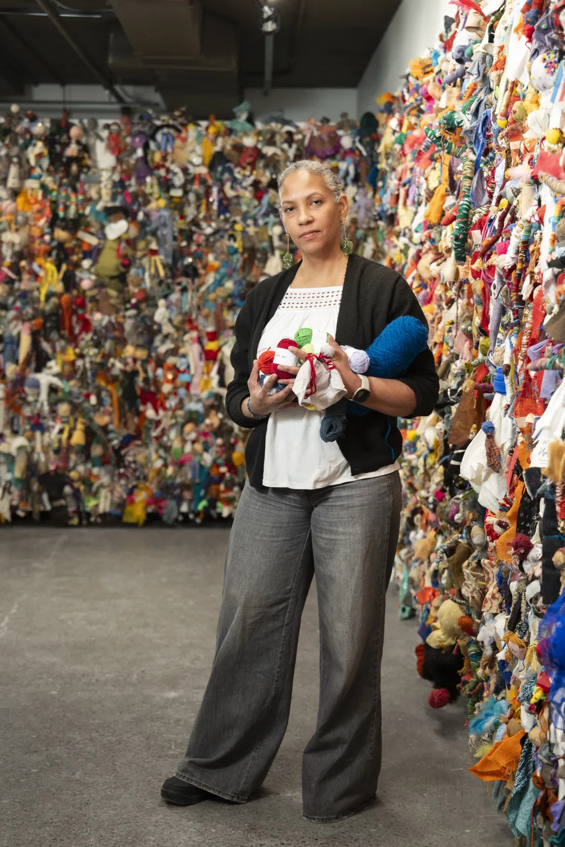 Professor Rochele Royster standing in a gallery holding a cloth doll.