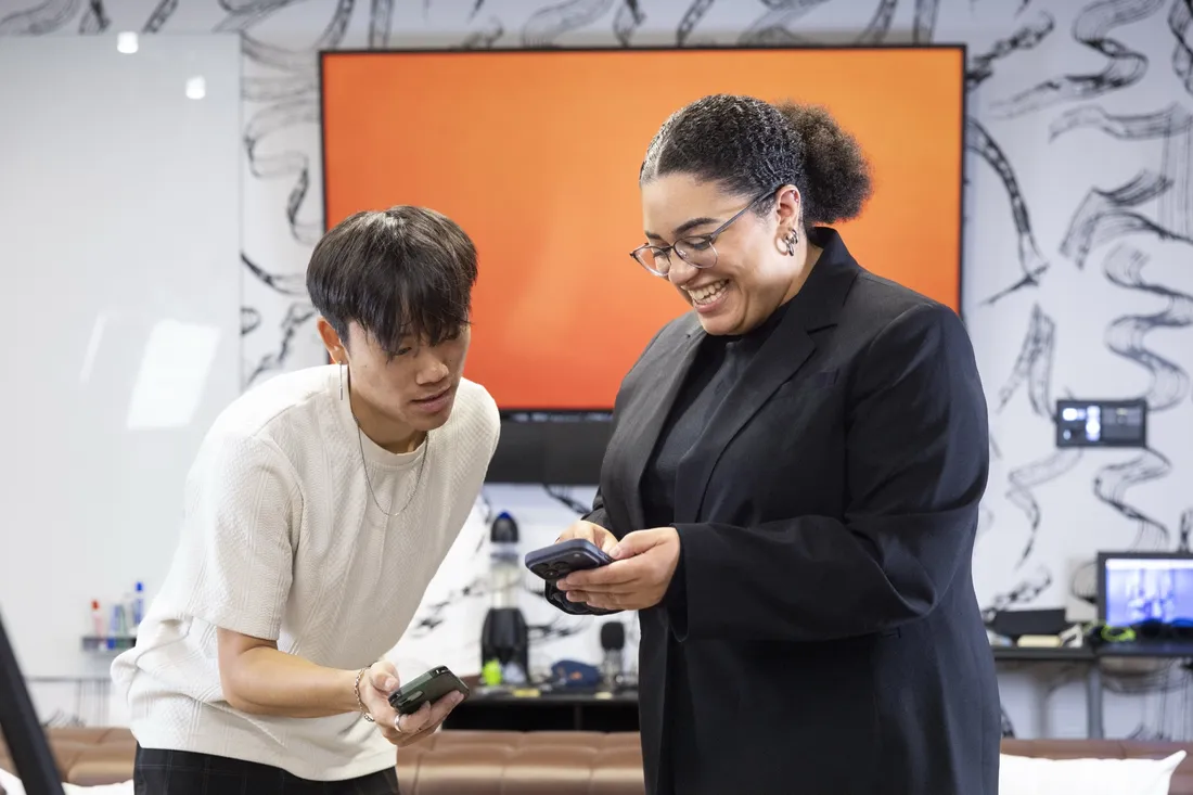 Alumna Carmella Boykin '21 holding up her phone and networking with a student.