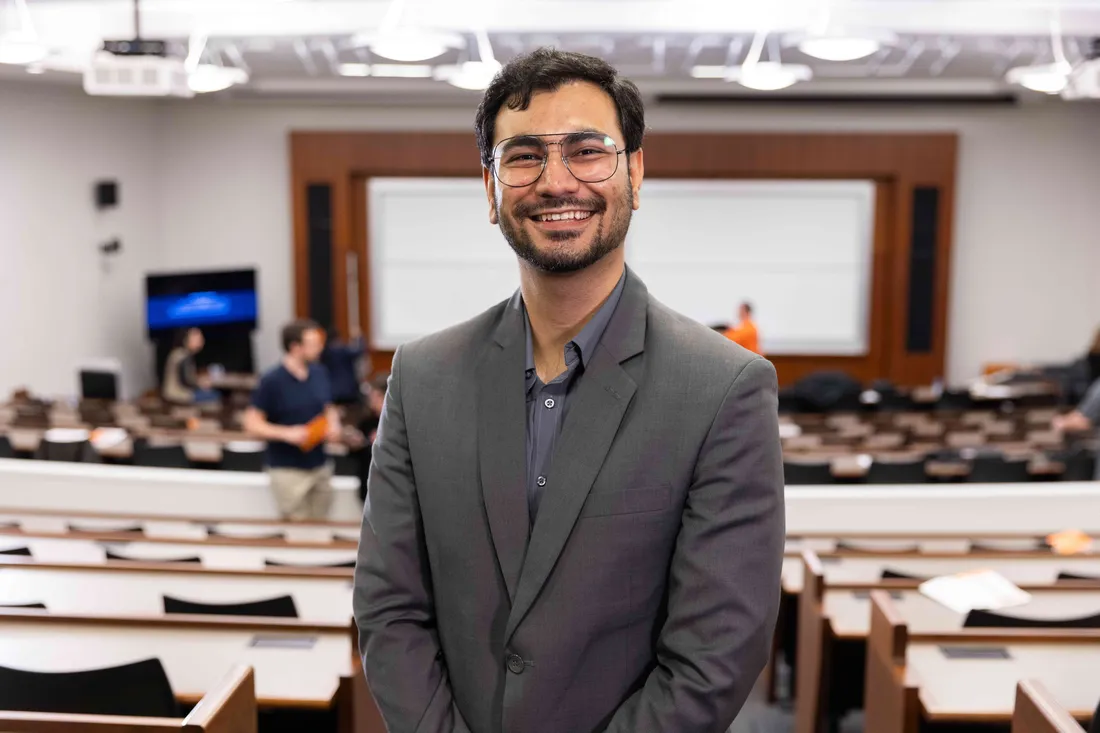 Whitman School of Management student standing and smiling in a classroom.