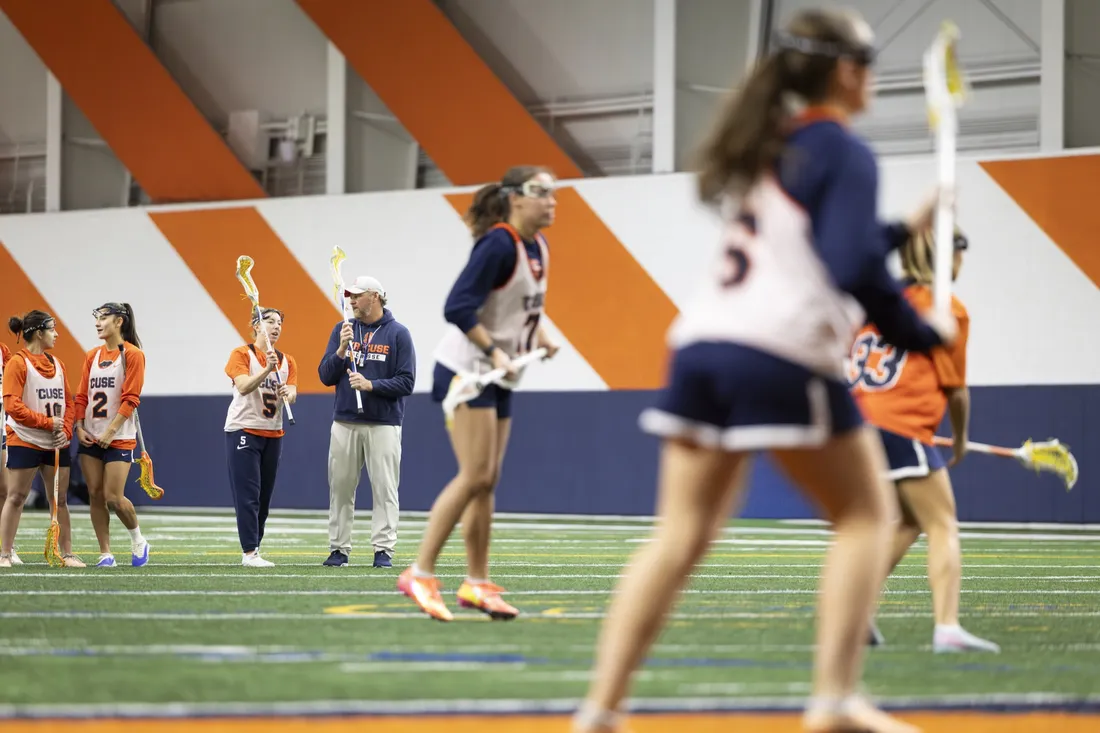 Regy Thorpe speaking with a member of Syracuse University's women's lacrosse team during practice.