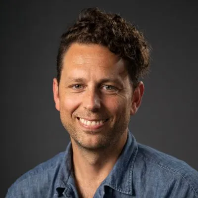 Michael Hicks smiling with a navy blue polo on.