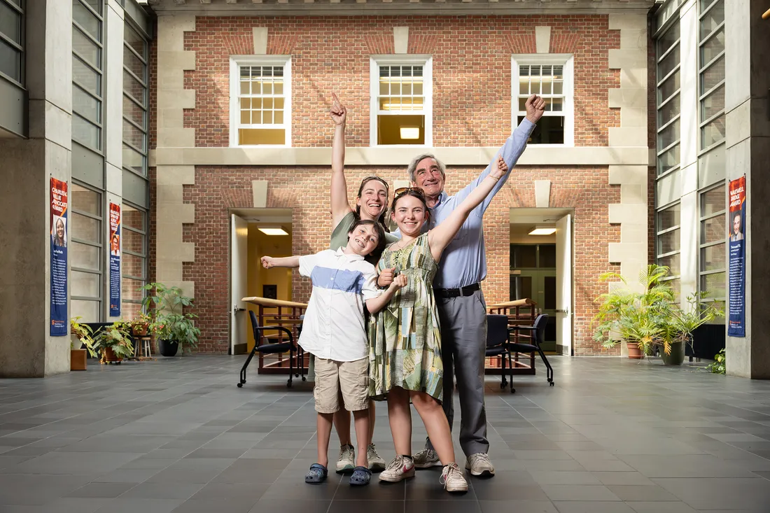 People with their arms up posing for picture in the Maxwell School of Business at Syracuse University.