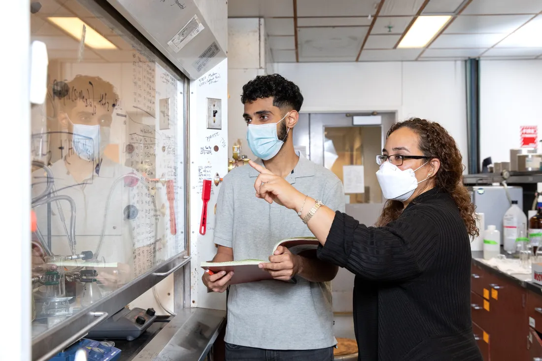 two people in face masks looking at a display in a laboratory