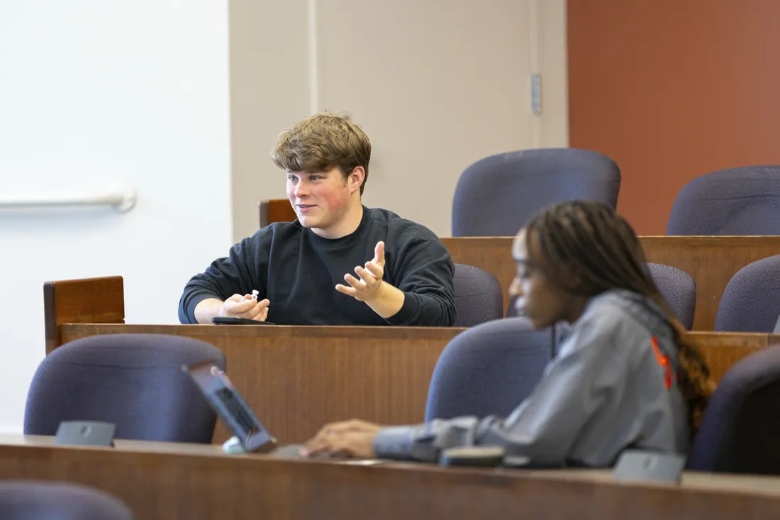 Two students sitting in a lecture hall.