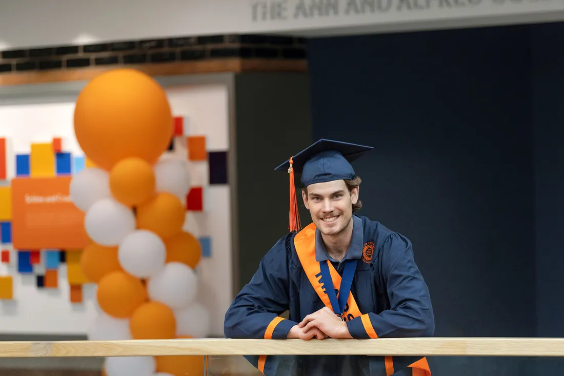Brady McKenna standing and smiling on a railing.