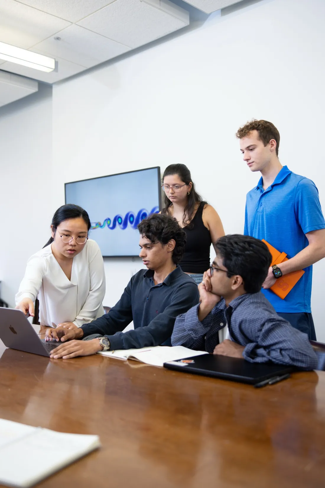 Professor Yiyang Sun pointing to a computer and speaking with undergraduate research students.