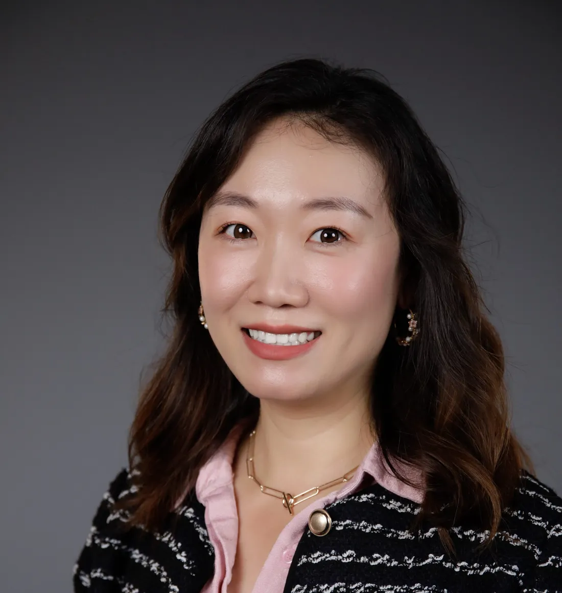 Yuxin Zhao smiling in a black blazer and pink button up.