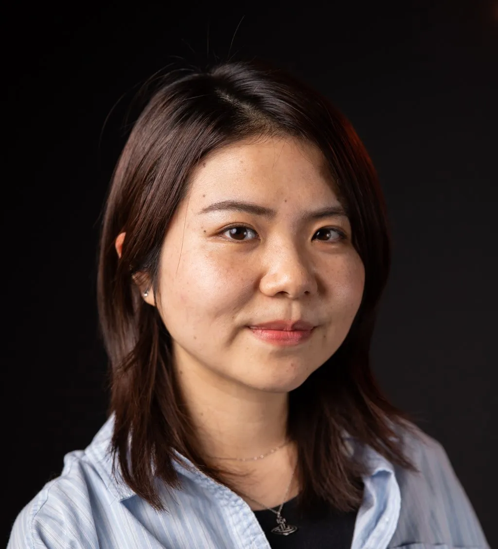 Man Wang smiling in a blue button up top.