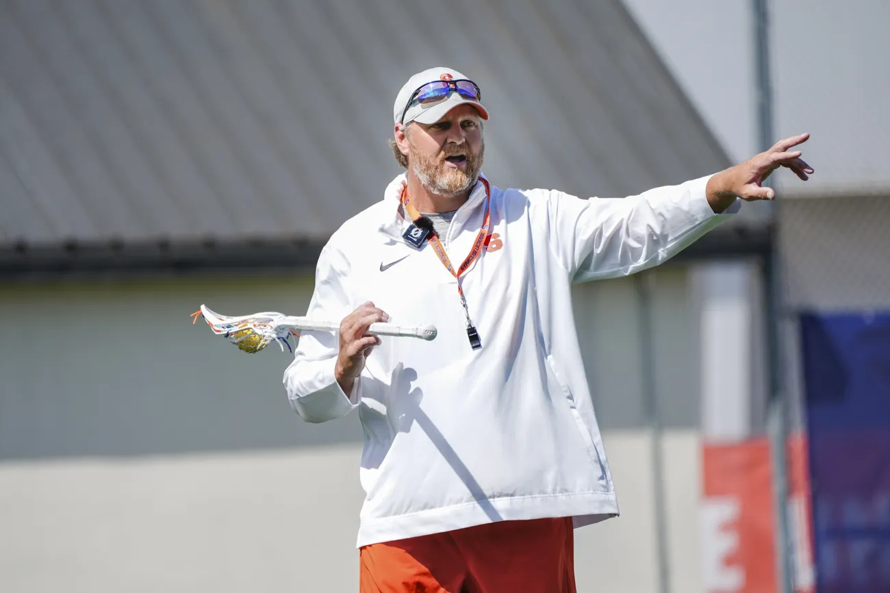 Women's lacrosse coach Regy Thorpe '01 holding a lacrosse stick and coaching at practice.