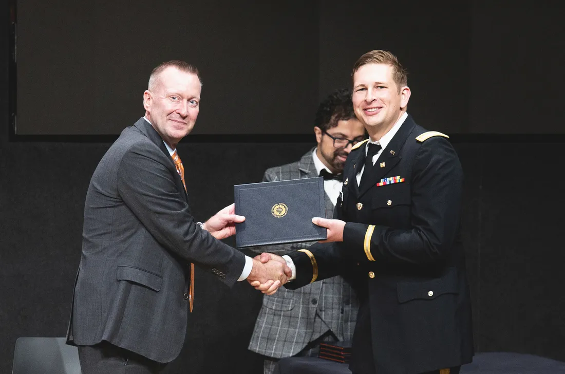 Portrait of Haynie shaking Schultz's hand as Shultz receives an award.