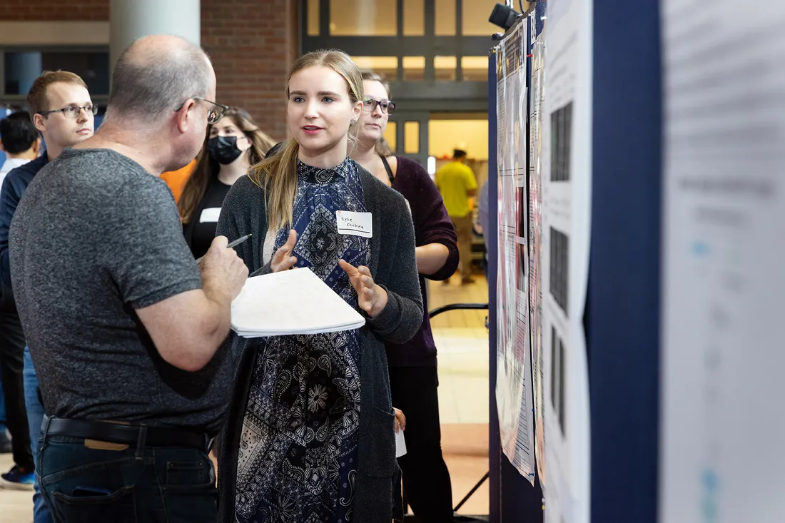 Medium shot of Kylie Chichura presenting a poster to people standing nearby.