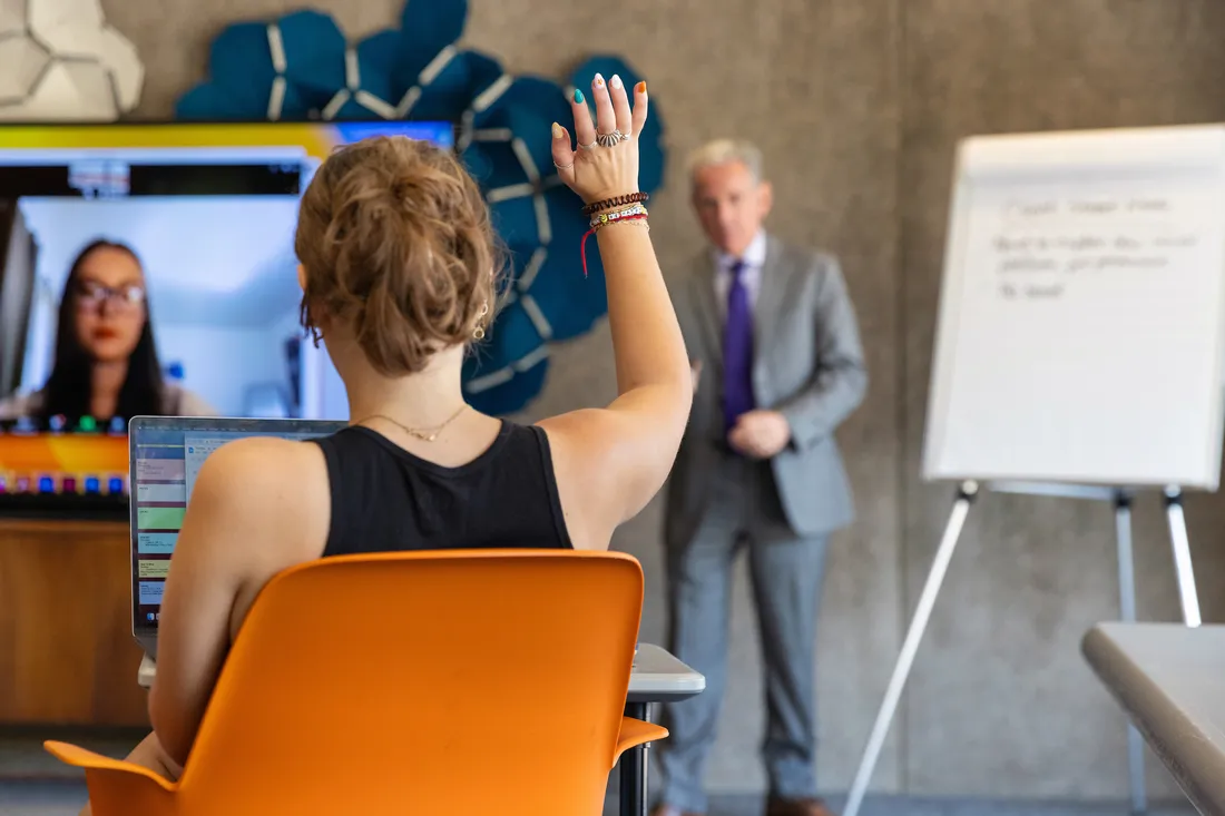 Person holding their hand up in a classroom.