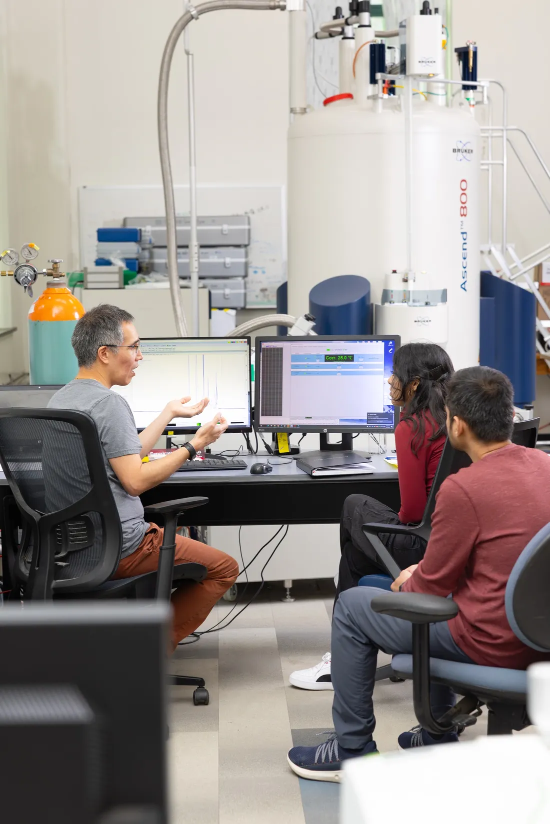 Carlos Castañeda sitting at a computer with two student researchers.