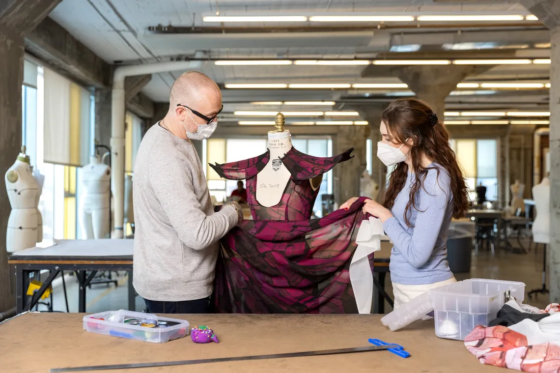 Isabelle Collins and Todd Conover adjusting a dress on a mannequin.