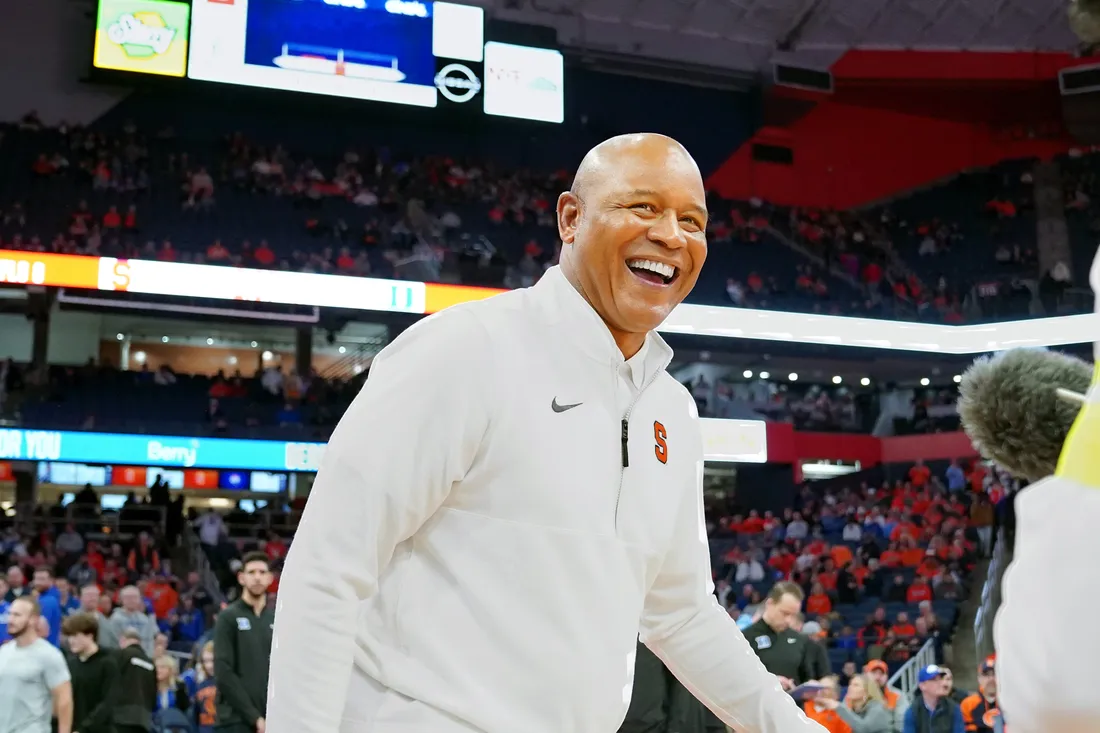 Man on basketball court walking and smiling.