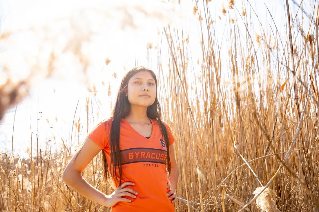 Student standing in a field of reeds.