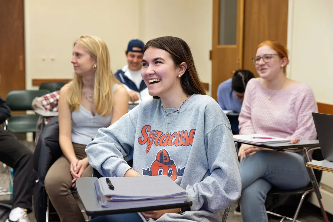 Student wearing Syracuse University sweatshirt sits in classroom.