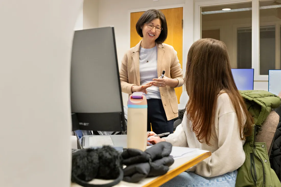 A person talking to someone at a computer.